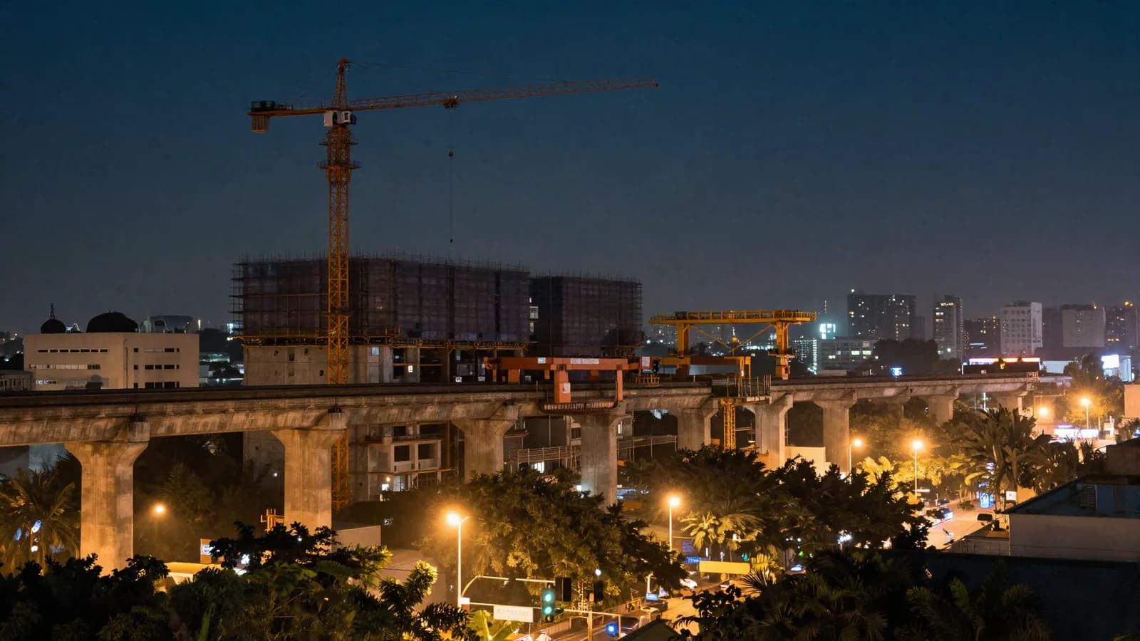 An elevated metro viaduct under construction in a Southeast Asian city at dusk